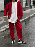 Red loose fit two-piece suit comprising a long-sleeved coat and trousers on a rack.