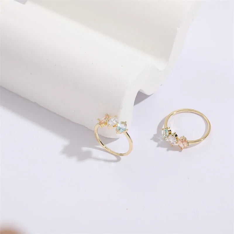 Women's gold-coloured ring with a horse eye design and three coloured zircon stones on a geometric band.