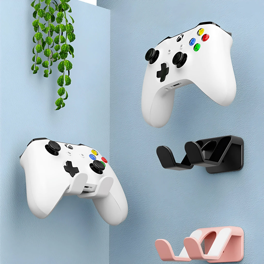 Black universal wall hanging rack mounted on a white tile wall holding two game controllers.