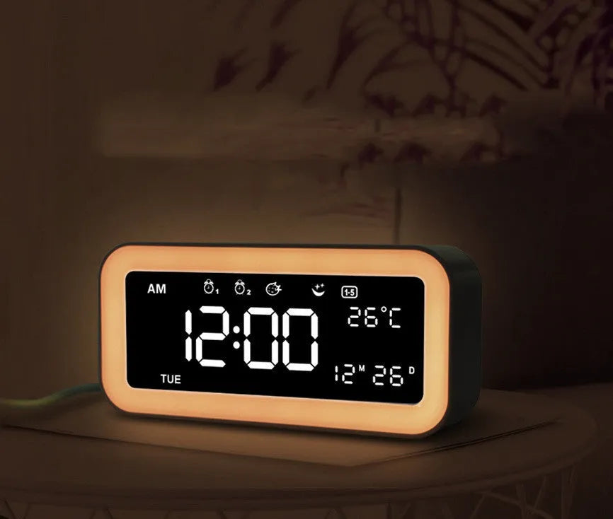 Blue rectangular LED digital alarm clock with multicoloured lighting and Bluetooth speaker on a bedside table.