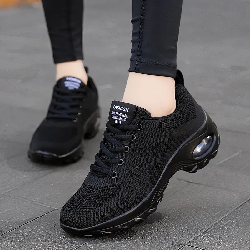 Red and black women's low-top mesh sneakers with front laces and a round toe, showing a mid-heel sole.