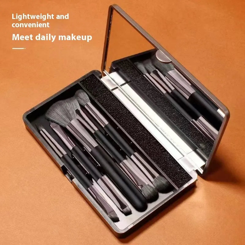 Makeup brush set with mirror open, showing silver and gold eyeshadow brushes inside a compact case.