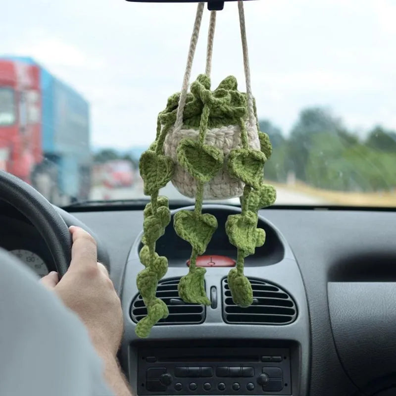 Green and white knitted wool car plant ornament with basin base and hanging rope.
