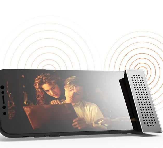 A small black plastic phone amplifier stand holding a smartphone on a desktop.