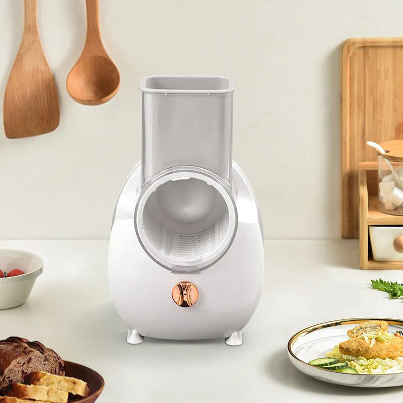 White electric vegetable slicer with rotary grater, feeding port, and three blade pairs on kitchen counter