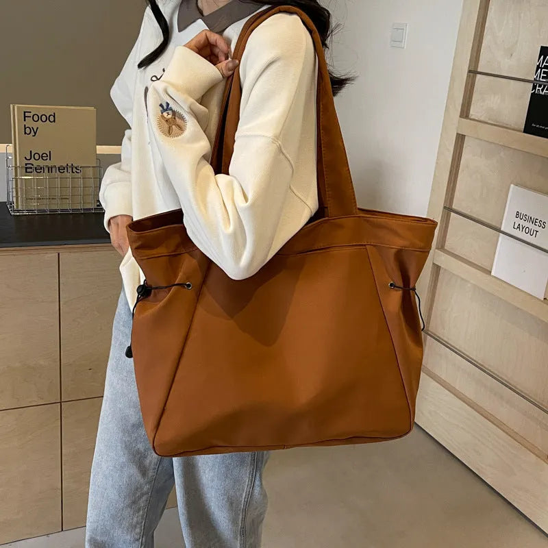 A soft folding Oxford cloth tote bag in a choice of five colours: black, light grey, dark grey, brown, and purple.