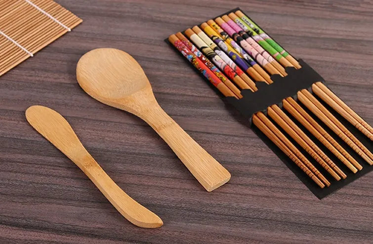 White plastic sushi tool set with moulds for rolls and Nigiri and a rice paddle on a light background