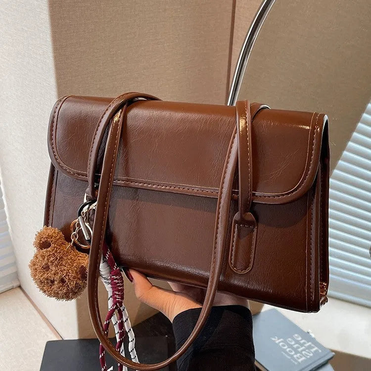 Brown structured women's PU shoulder bag with double straps, a pendant, and a horizontal square shape.