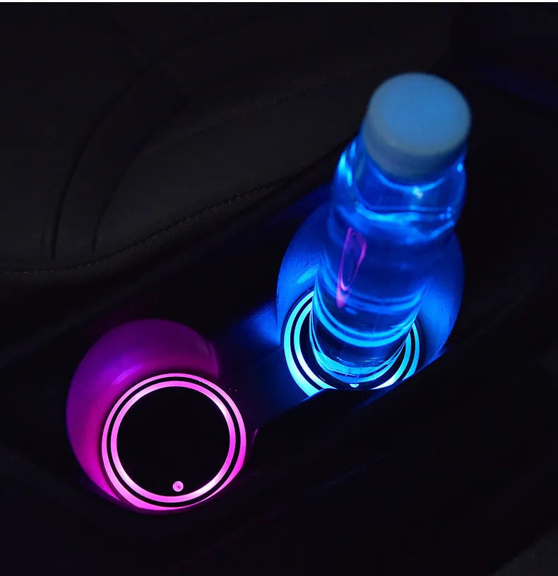 Colourful LED light-up coaster for car cup holder with USB cable on a car centre console.