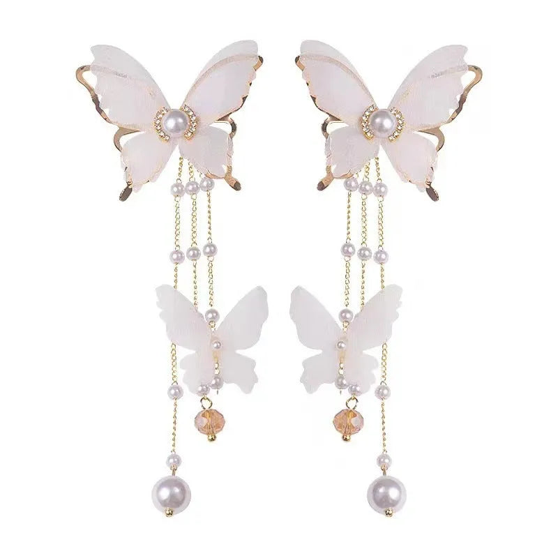 White butterfly-shaped earrings with lace patterns, pearl rhinestones, and a dangling tassel on a copper alloy base.