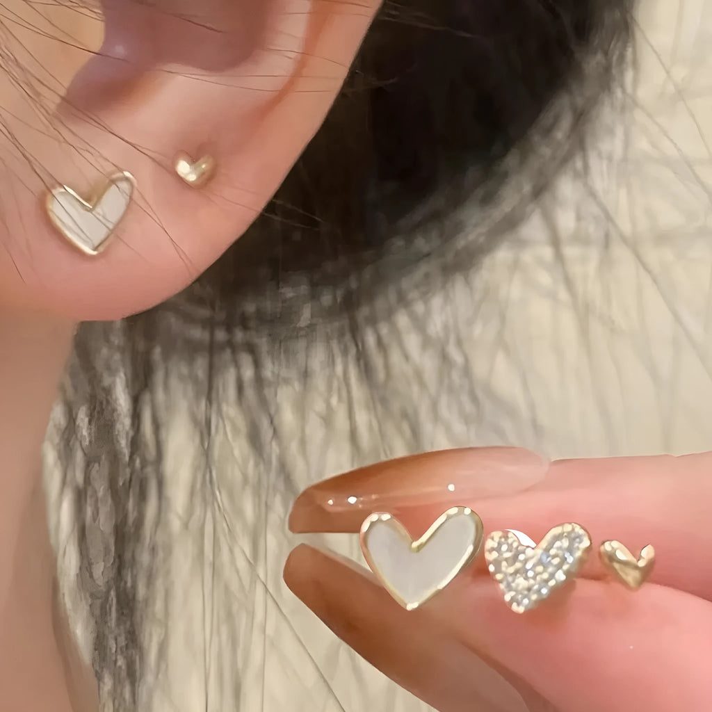 Three pairs of heart-shaped alloy earrings with electroplated finishes in gold, black, black-white, and pink colours