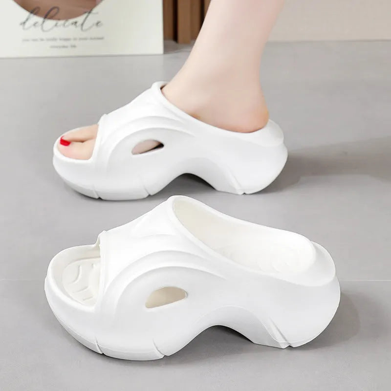 Women's white thick-soled EVA beach slippers with round toe on sand.