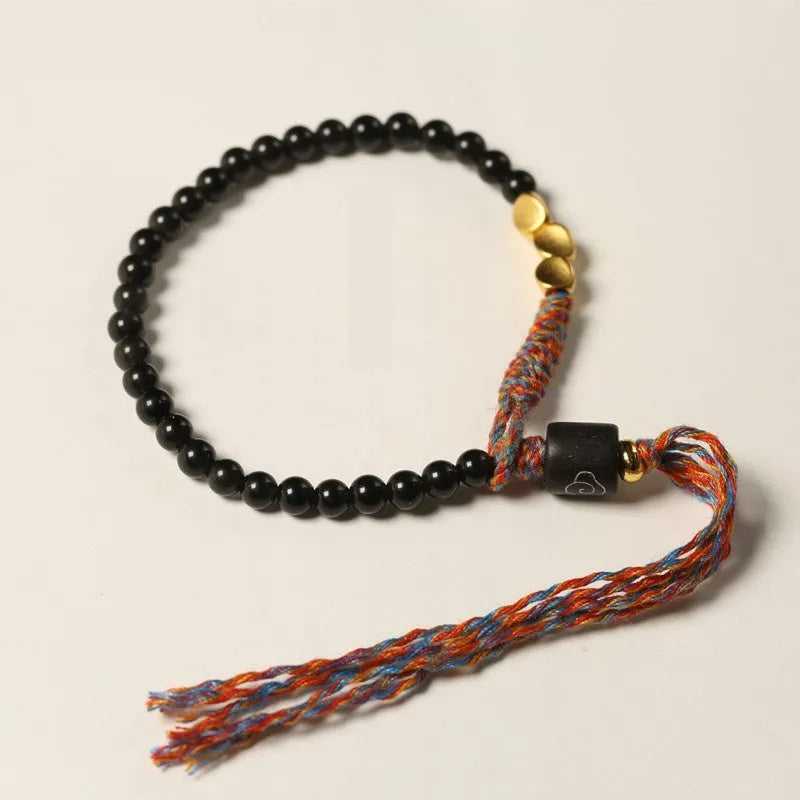 Hand-woven obsidian stone bracelet on a wrist, showing its dark colour and 4mm width.