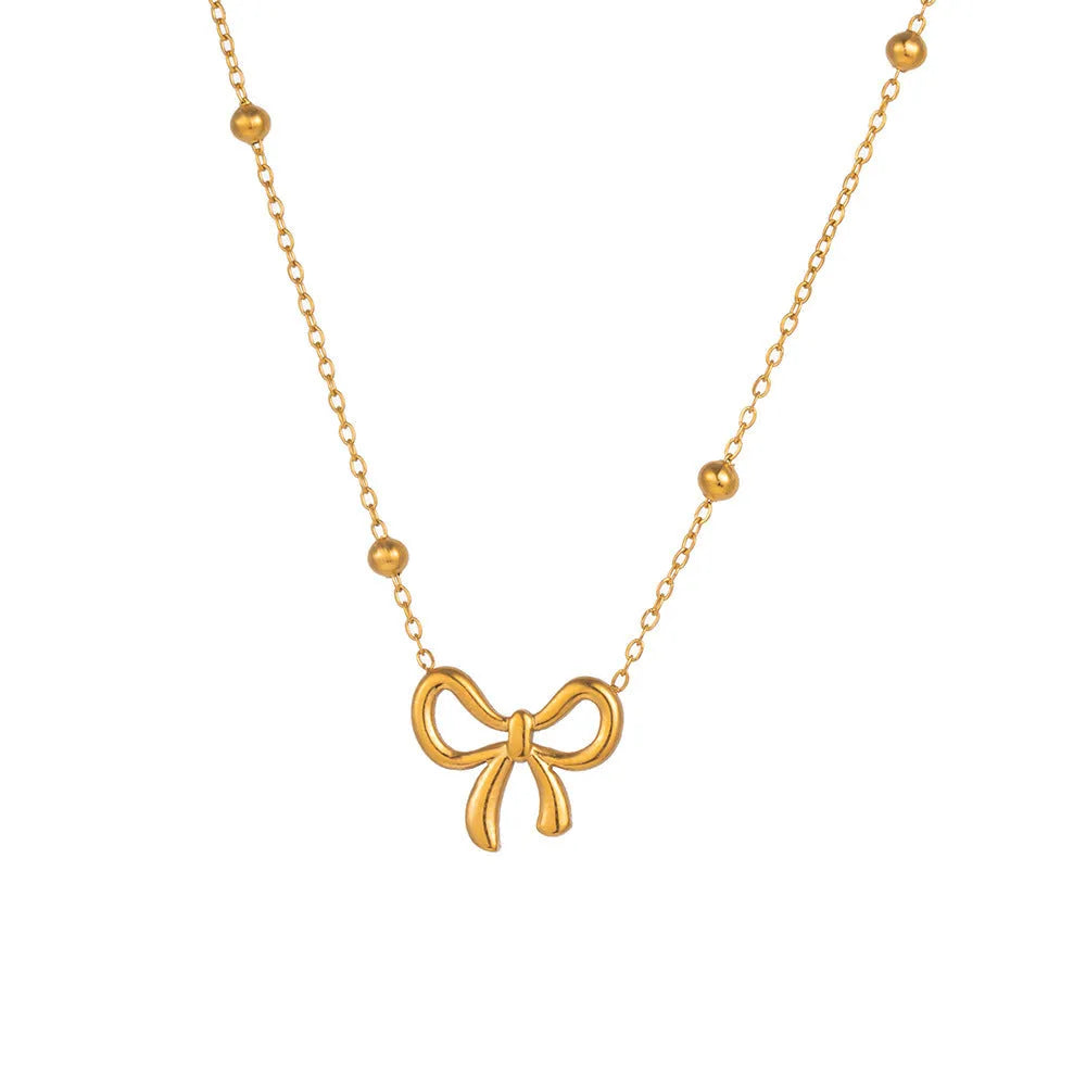 Gold electroplated women's bow necklace with cross chain design on white background