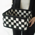 Checkerboard pattern black and white felt storage basket with folded sides.