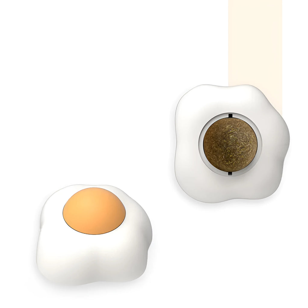 Soft plush catnip ball toy with adhesive base sticking to a wall for interactive feline play