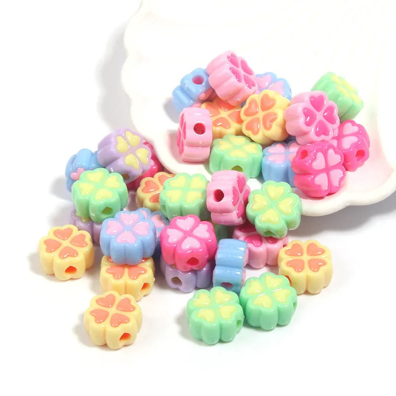 Frosted acrylic four-leaf clover shaped beads in mixed colours on white background