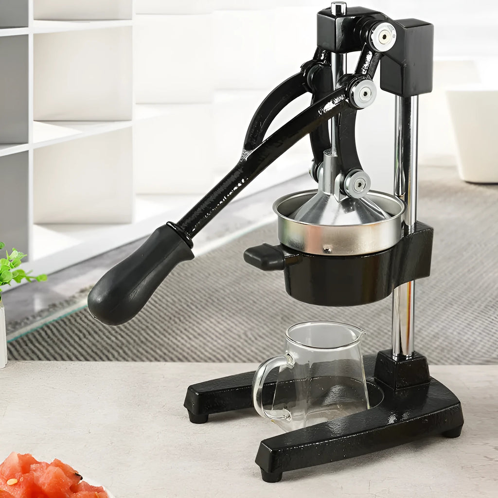Tall black manual citrus juicer with cast iron base and stainless steel press cone on a kitchen counter