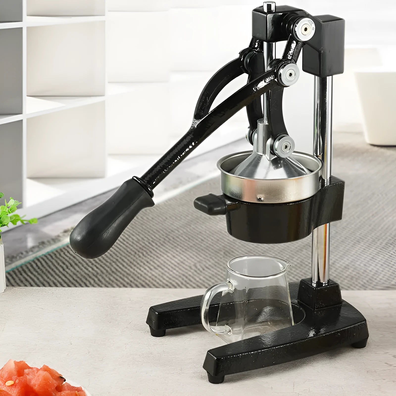 Tall black manual citrus juicer with cast iron base and stainless steel press cone on a kitchen counter