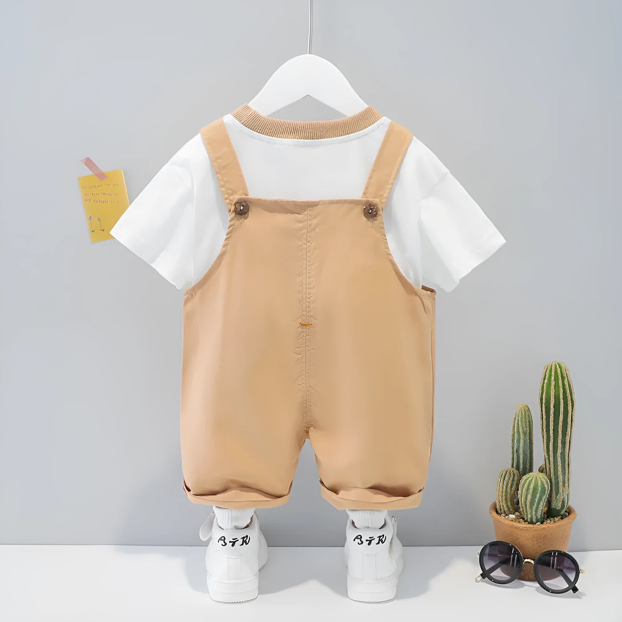 Yellow cotton baby overalls with cartoon print, short sleeves, and adjustable straps on a hanger.