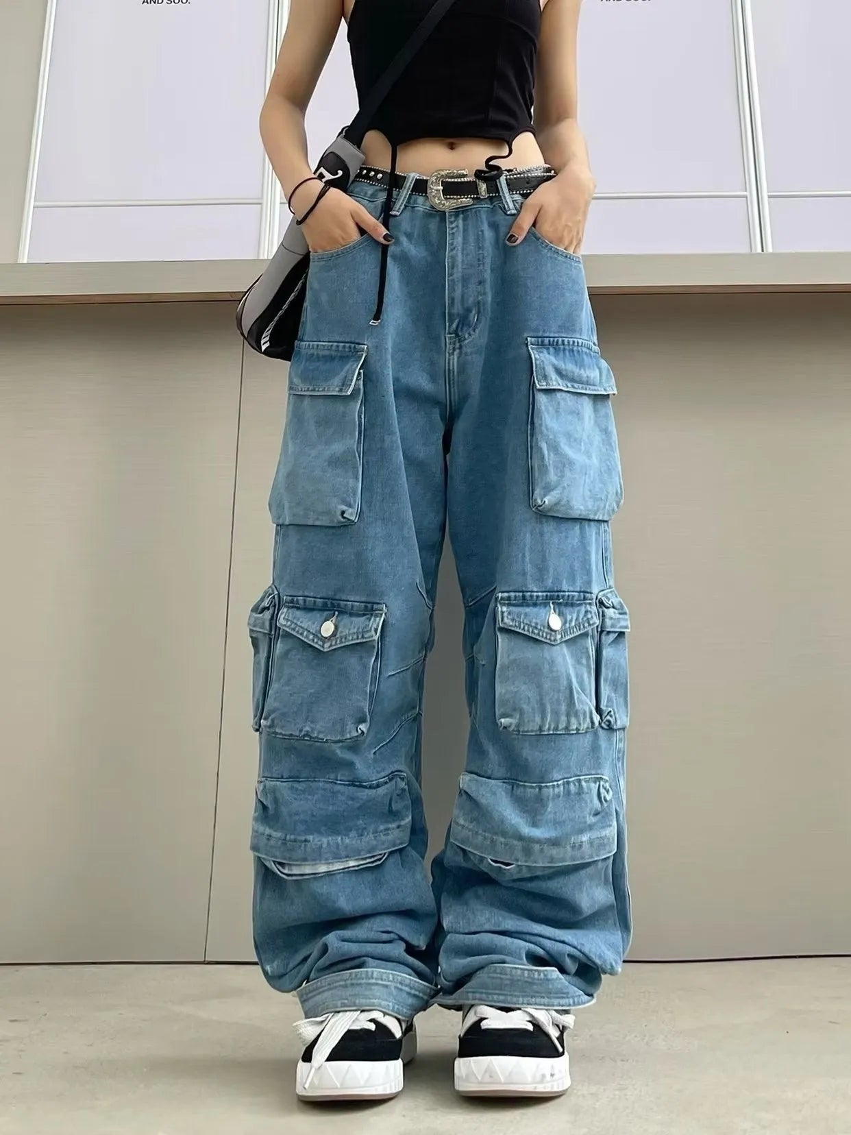 Woman wearing blue tie-dyed high waist wide leg jeans with multiple pockets in a street style setting.