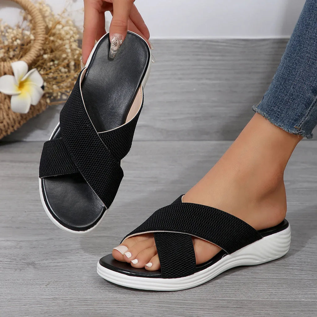 Women's black wedge peep-toe slippers with a cross-strap design and thick rubber sole.