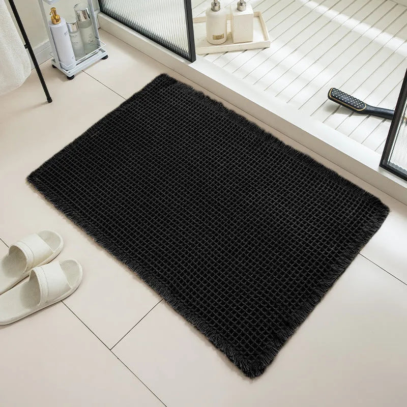Beige and white checkered woven polyester bathroom floor mat on tiles.