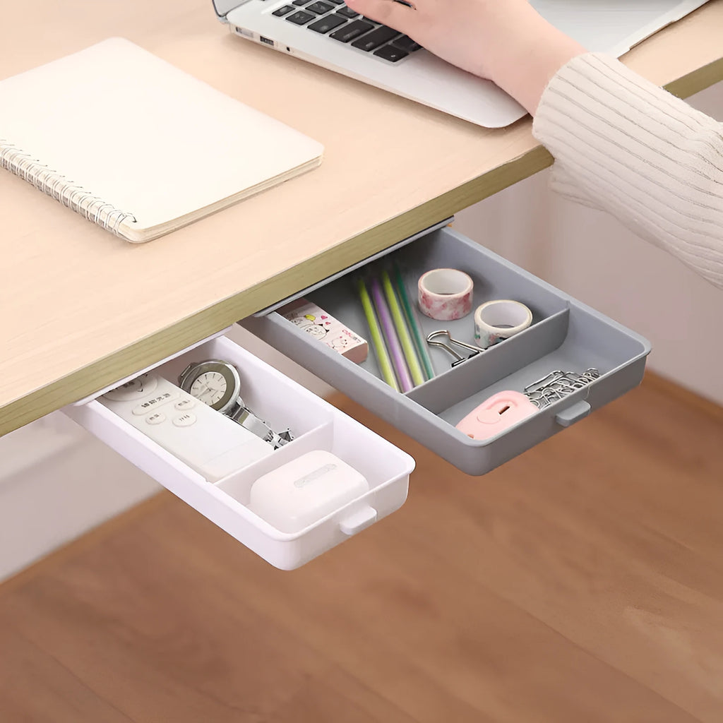 White plastic adhesive under-table storage box with a cover open, showing internal grid compartments.