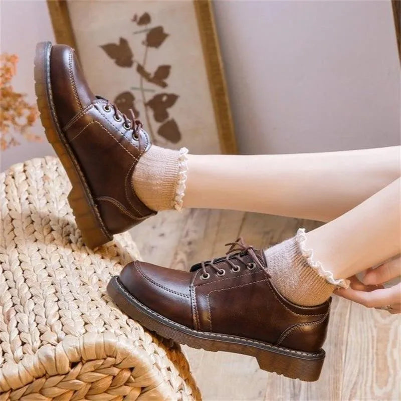 Women's preppy style brown retro Mary Jane pumps with round toe and front lace-up closure on a white background.