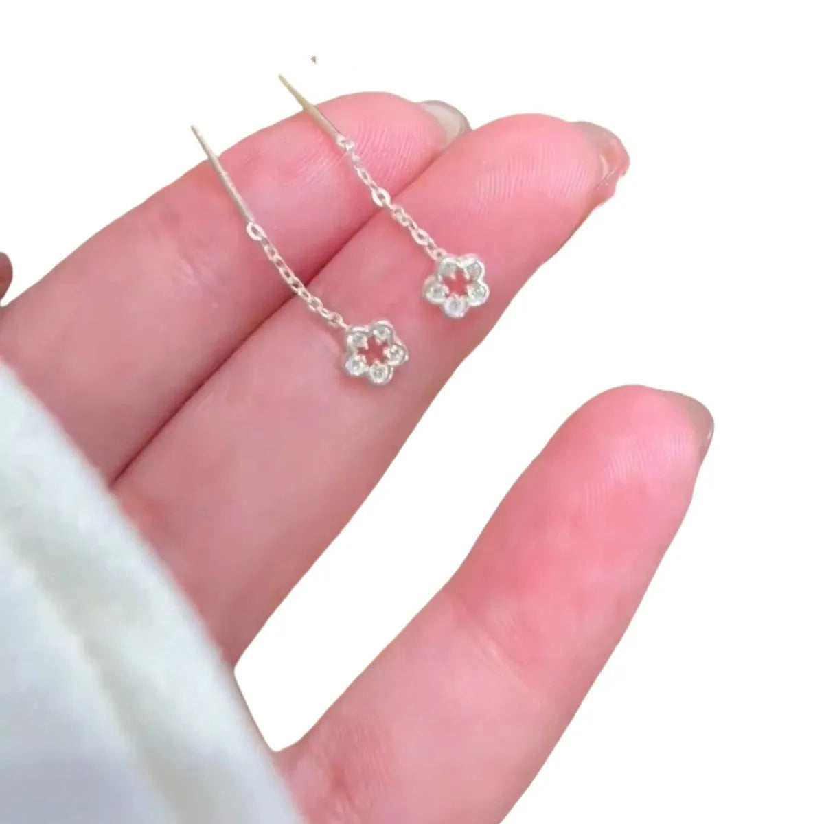 A pair of silver-coloured alloy drop earrings with a hollow floral petal design.