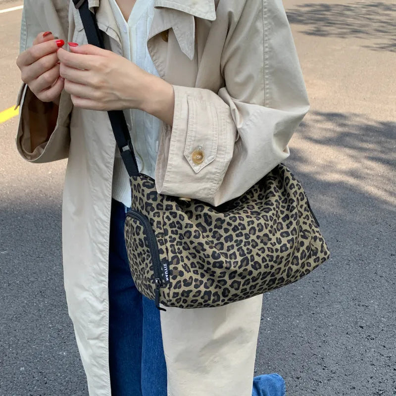 Cloth messenger bag with leopard print pattern showing cross-body strap and stitching details