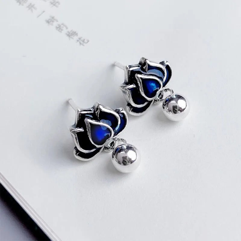 Close-up of blue lotus flower and seedpod tassel design on silver alloy ear studs