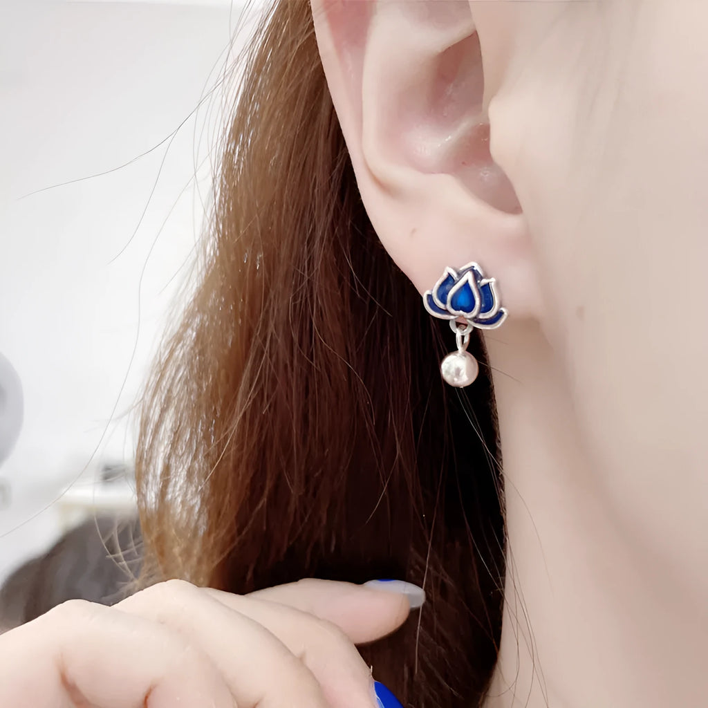 Close-up of blue lotus flower and seedpod tassel design on silver alloy ear studs