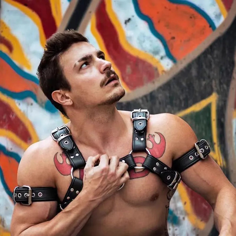 Black leather chest strap for men with metal buckle and rivet details on a mannequin.