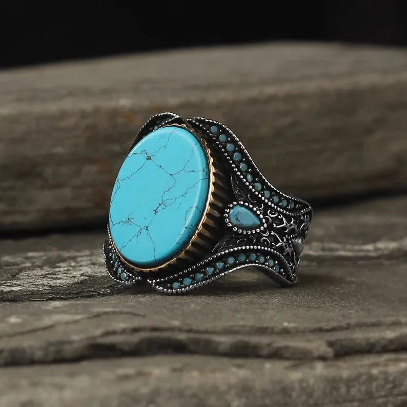 Men's antique silver alloy ring with a turquoise-coloured centre on a finger, showing its simple round design.