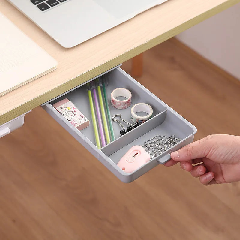 White plastic adhesive under-table storage box with a cover open, showing internal grid compartments.