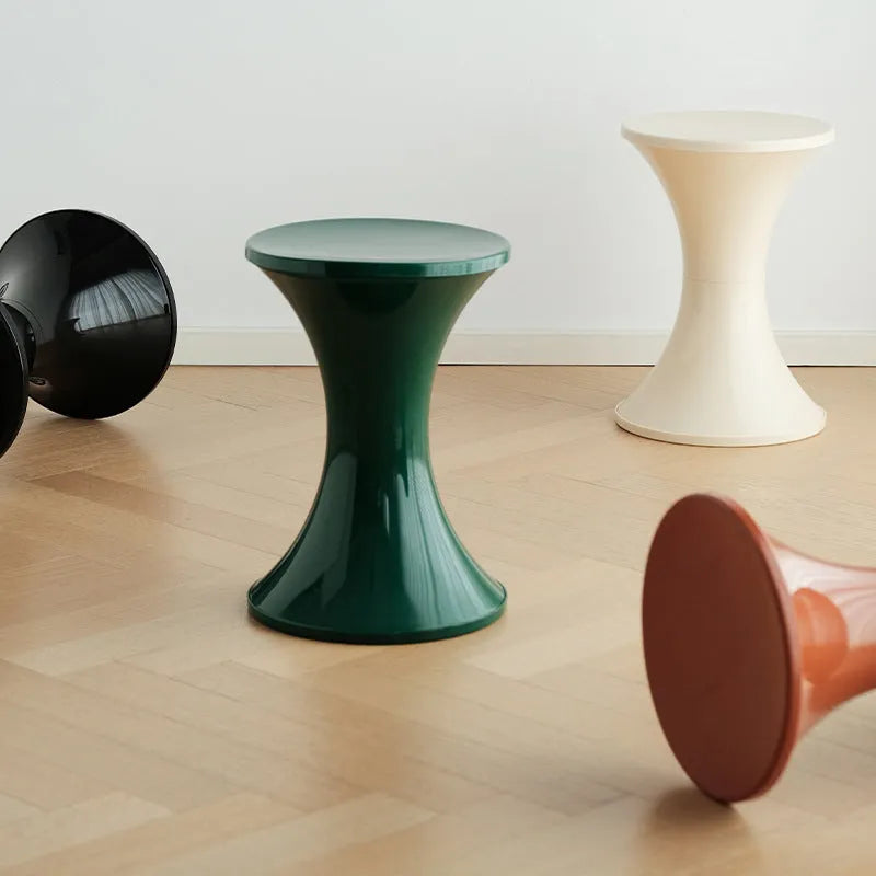 Hourglass-shaped plastic shoe changing stool in green colour on a wooden floor.