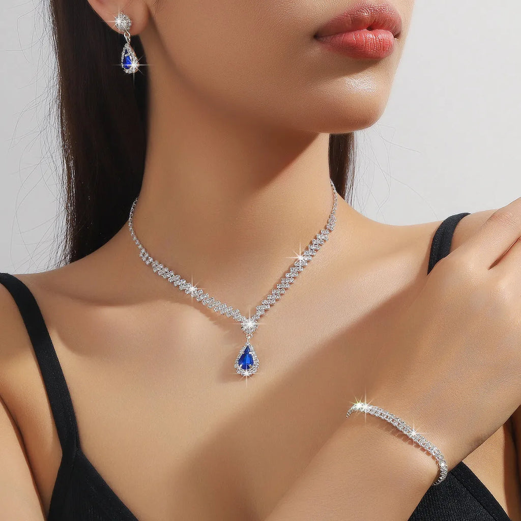 Women's claw chain necklace and drop rhinestone earrings set in blue on a white background.