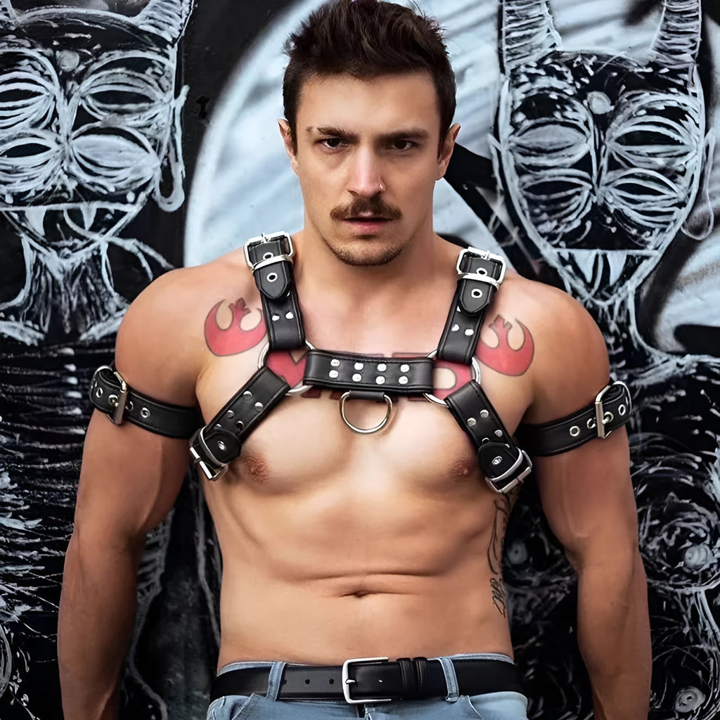 Black leather chest strap for men with metal buckle and rivet details on a mannequin.