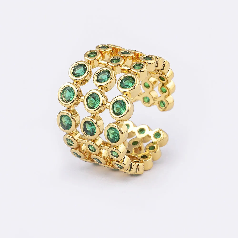 Gold coloured wide band ring with green zircon stones, shown from the side.