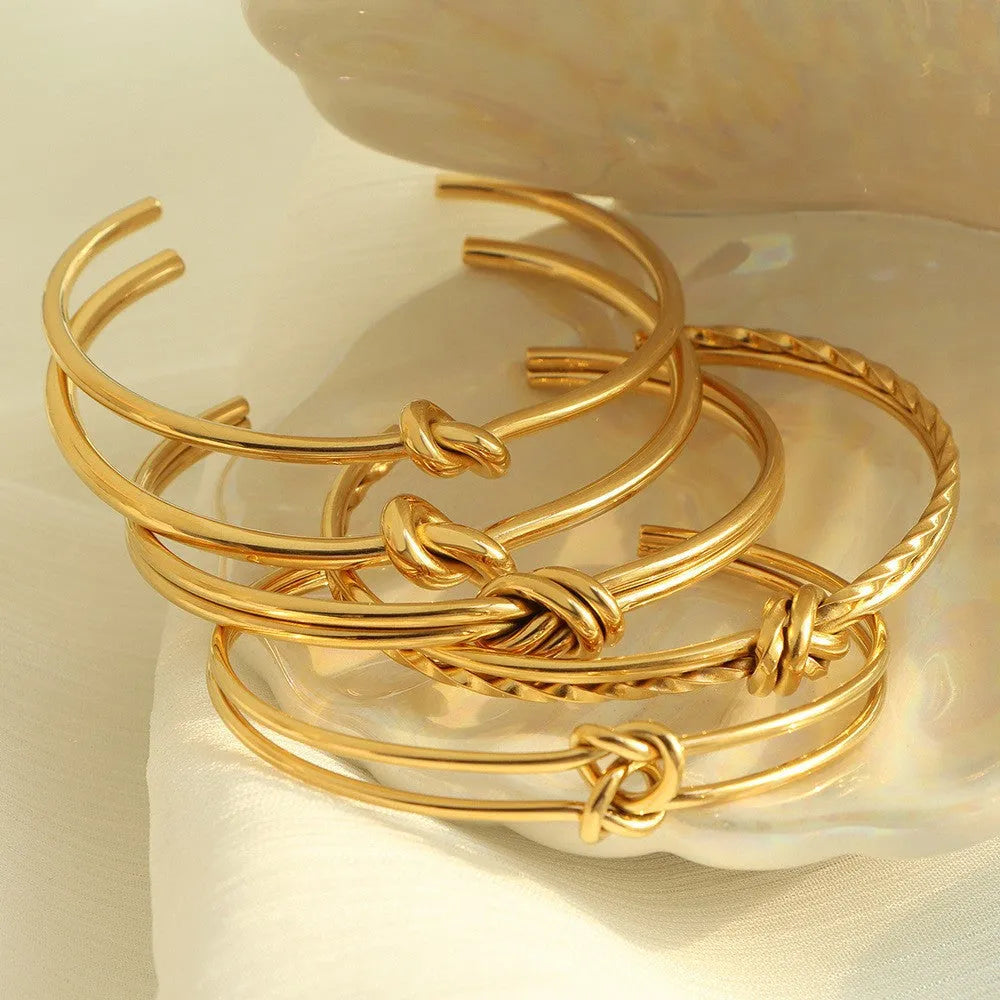 Adjustable open C-shaped double-layer bracelet in gold plating with a knotted design on stainless steel.
