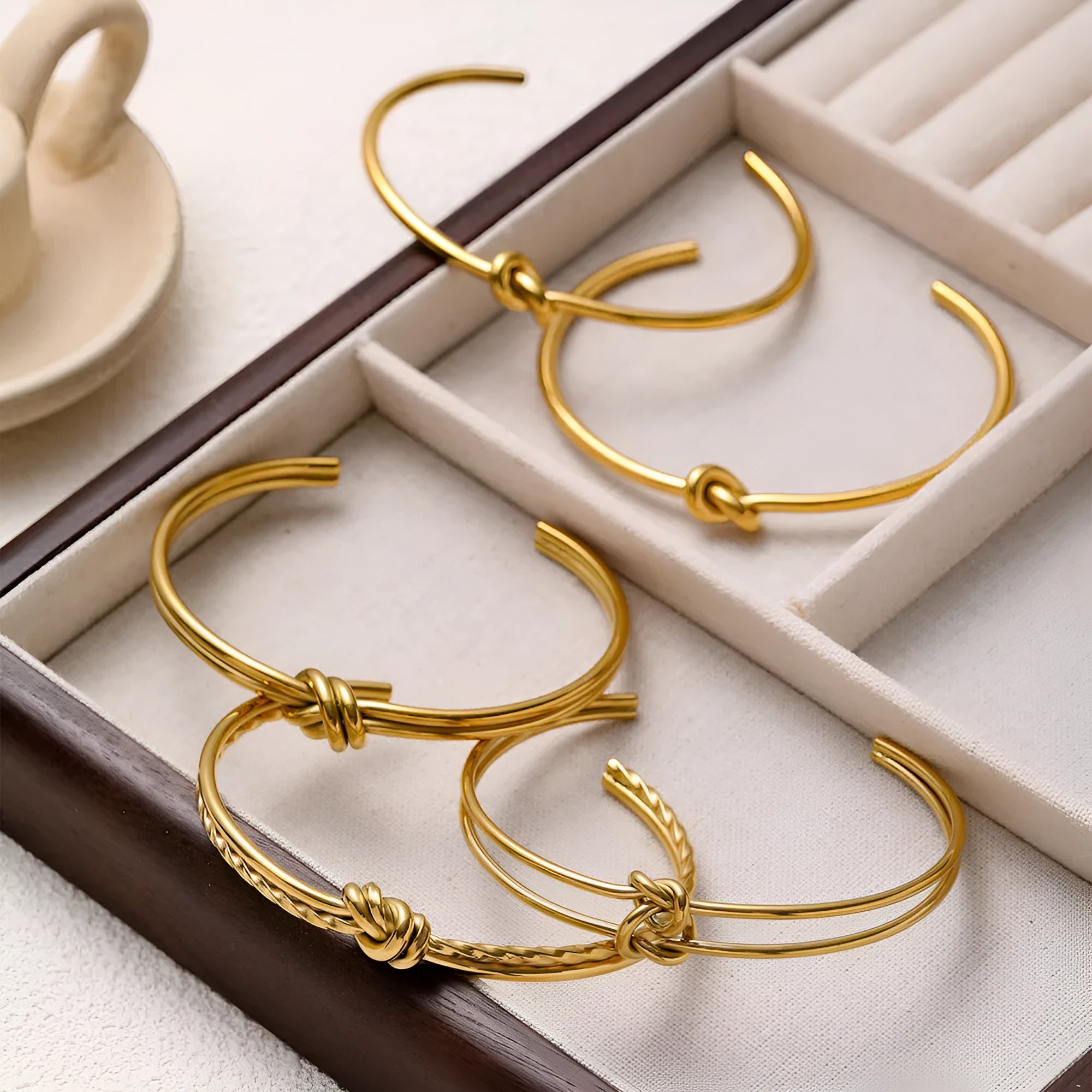Adjustable open C-shaped double-layer bracelet in gold plating with a knotted design on stainless steel.