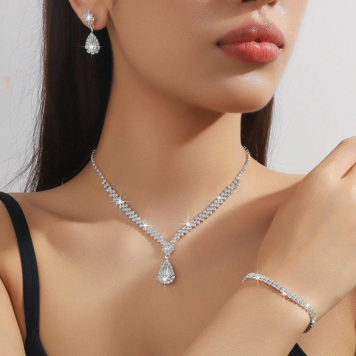 Women's claw chain necklace and drop rhinestone earrings set in blue on a white background.