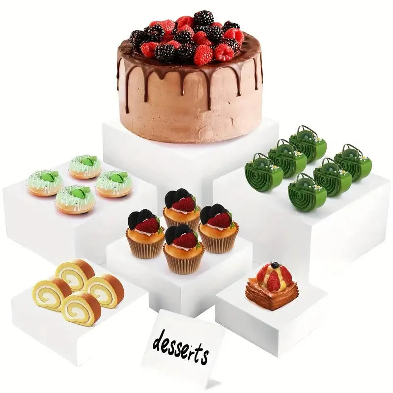 Set of six white plastic cube-shaped dessert display stands arranged on a desktop.