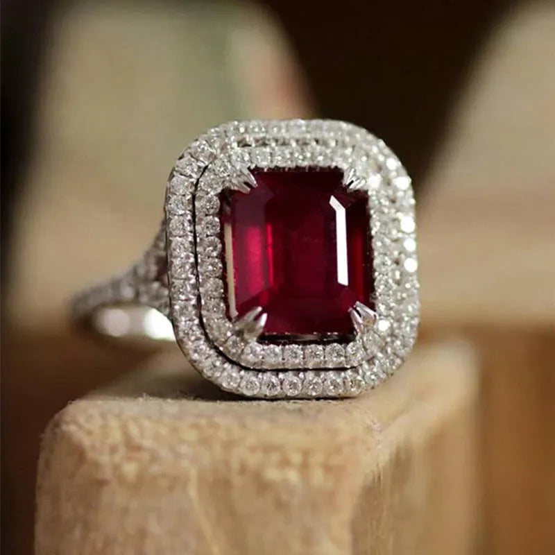 Red geometric square copper ring with clear princess-cut rhinestones, shown on a finger.