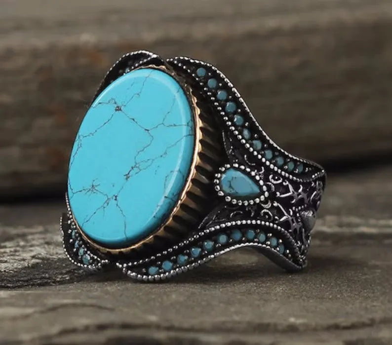 Men's antique silver alloy ring with a turquoise-coloured centre on a finger, showing its simple round design.