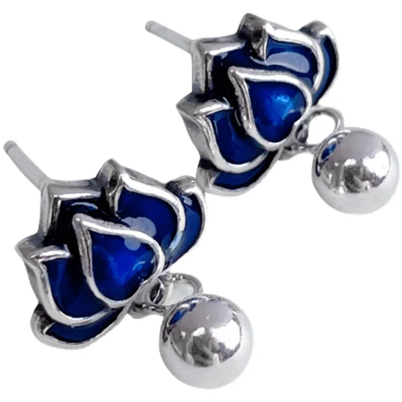 Close-up of blue lotus flower and seedpod tassel design on silver alloy ear studs