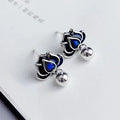 Close-up of blue lotus flower and seedpod tassel design on silver alloy ear studs