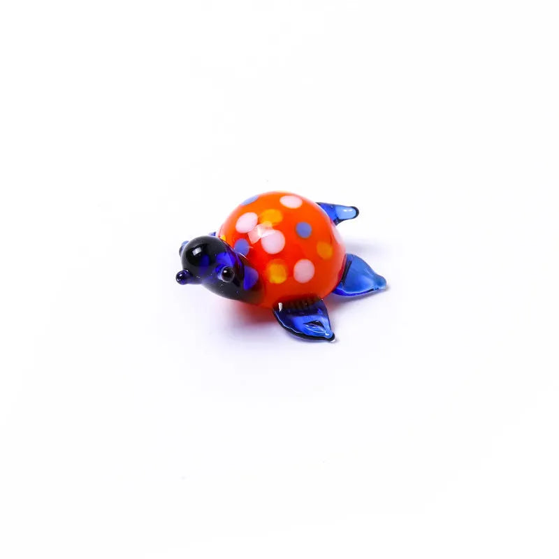 Geometric glass turtle ornament in a blue head and blue shell colour variant on a desktop.