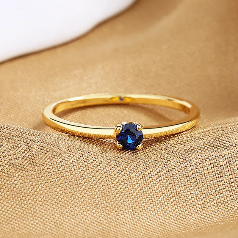 A simple single diamond fine circle ring for women in copper, shown in blue, green, red, and white colour options.